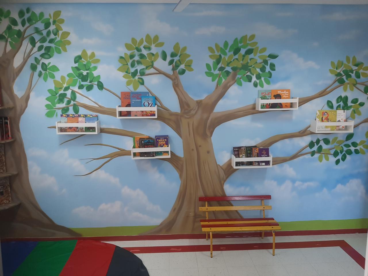 Cantinho da leitura com painel de árvore e livros